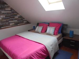 um quarto com uma cama com almofadas cor-de-rosa e azuis em Les Cygnes em Criel-sur-Mer
