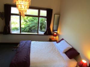 a bedroom with a bed and a window at Greenstone Retreat in Kumara