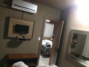 - une chambre avec un miroir, une télévision et un lit dans l'établissement Residencial Quatro Estações, à Canela