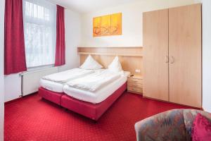 a bedroom with two beds and a red carpet at Gästehaus Bakker in Norderney