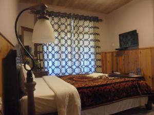 a bedroom with a bed with a lamp and a window at The Hill Town Cottage in Nuwara Eliya