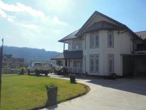 a white house with a truck parked in a yard at The Hill Town Cottage in Nuwara Eliya