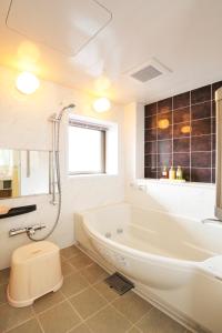 a white bathroom with a tub and a toilet at Hotel Global View Kushiro in Kushiro