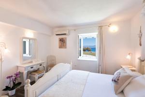 a white bedroom with a bed and a window at Ambelas Mare Apartments in Ambelas