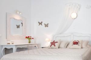 a white bedroom with a white bed and a table at Ambelas Mare Apartments in Ambelas