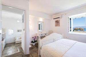 a white bedroom with a white bed and a window at Ambelas Mare Apartments in Ambelas