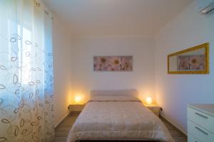 ポルトフェッラーイオにあるAppartamento Molo Bの白いベッドルーム(ベッド1台、ランプ2つ付)