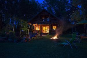 una cabaña de madera con fuego en el patio por la noche en Neti Holiday House, en Saunja