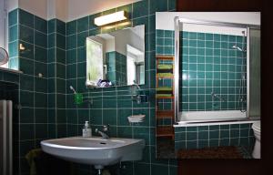 a green tiled bathroom with a sink and a mirror at Villa Ludwig Fewo in Otterndorf +32 photos