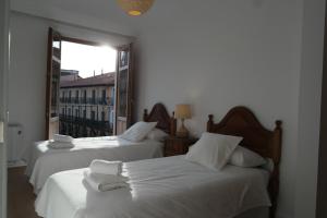 2 Betten mit weißer Bettwäsche in einem Zimmer mit Fenster in der Unterkunft NG Plaza Mayor in León