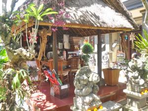 a restaurant with a thatch roof and chairs and plants at Depa House in Ubud