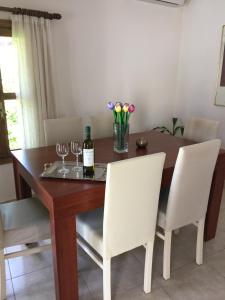 uma mesa de jantar com cadeiras brancas e uma garrafa de vinho em Summer Knights in Ilha de Rhodes