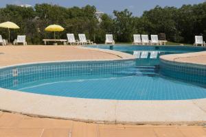 une grande piscine avec des chaises et des parasols dans l'établissement Olhos Do Mar Albufeira, à Albufeira