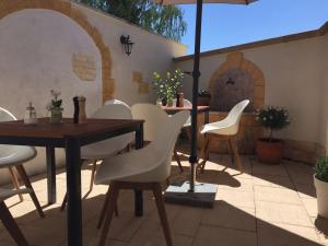 eine Terrasse mit einem Tisch, Stühlen und einem Sonnenschirm in der Unterkunft Gästehaus Elzblick in Rust