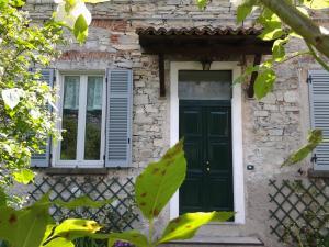 Casa de piedra con puerta verde y ventanas en Casa Giardino, en Gravedona