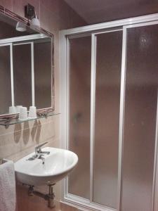 La salle de bains est pourvue d'une douche et d'un lavabo blanc. dans l'établissement Casa Balea, à Balea