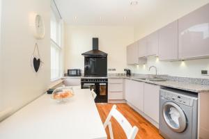 a kitchen with white cabinets and a stove top oven at Minster's Keep- Stylish Apartment Near York Minster in York