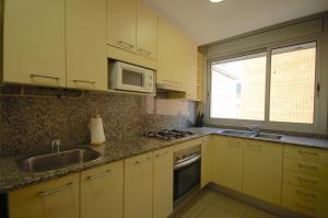 uma cozinha com armários amarelos, um lavatório e um micro-ondas em Lets Holidays Apartment Vinya del Pla em Tossa de Mar