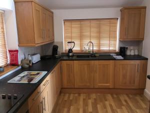 una cucina con armadi in legno e piano di lavoro nero di Maesbury Riverside a Oswestry