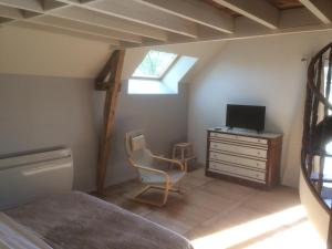 a bedroom with a bed and a desk with a television at La Chambre Montbrault in Fleurigné