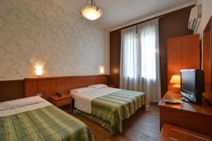 pokój hotelowy z 2 łóżkami i telewizorem w obiekcie Hotel Universo w Turynie