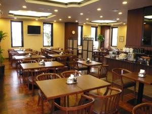 un restaurant vide avec des tables et des chaises en bois dans l'établissement Hotel Route-Inn Koriyama Minami, à Koriyama