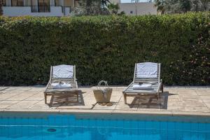 twee ligstoelen naast een zwembad bij Paphos Love Shack Apartment in Paphos City