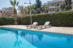 2 sedie a sdraio sedute accanto alla piscina di Paphos Love Shack Apartment a Paphos