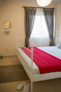 een slaapkamer met een witte wieg en een rode deken bij Paphos Love Shack Apartment in Paphos City