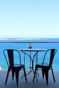 einen Tisch und zwei Stühle neben dem Wasser in der Unterkunft Panorama Mediterranea in St Paul's Bay