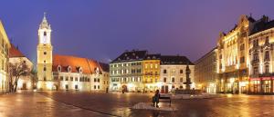 a person sitting on a bench in front of buildings at Excellent Location in Bratislava