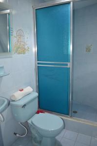 a bathroom with a toilet and a shower with a blue door at Hotel Elimar in Girardot
