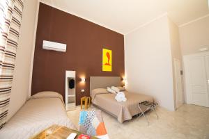 a bedroom with two beds and a brown wall at PC Boutique H Napoli Centro, by ClaPa Group in Naples