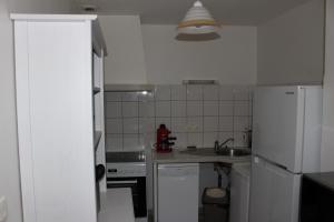 uma cozinha branca com um lavatório e um frigorífico em maison de bourg em Talmont