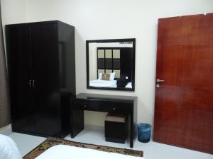 een slaapkamer met een zwarte dressoir en een spiegel bij Royal Home Furnished Apartments in Wadi ad-Dawasir