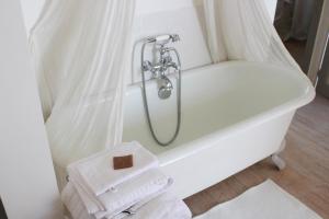 eine weiße Badewanne mit Duschvorhang und Handtücher in der Unterkunft L'Ancien Couvent Cahuzac in Cahuzac + 37 Fotos