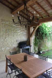 einen Holztisch mit Stühlen und einem Kronleuchter in der Unterkunft L'Ancien Couvent Cahuzac in Cahuzac