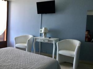 a bedroom with two chairs and a bed and a tv at Hotel Celine in Coti-Chiavari