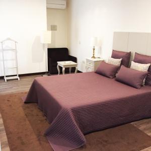 um quarto com uma cama grande e lençóis roxos em Hotel Central Jardim em Gerês