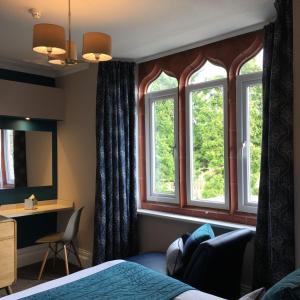 a hotel room with a bed and two windows at The Hideaway At Windermere (Adults only) in Windermere