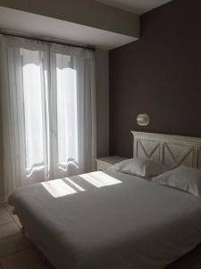 a white bed sitting in a bedroom next to a window at Hotel Bonaparte in Bastia