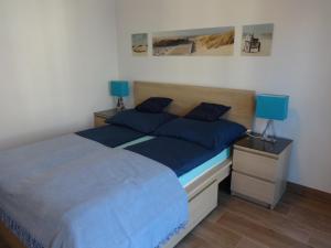 a bedroom with a bed with blue pillows on it at Apartament Aquamarina in Świnoujście