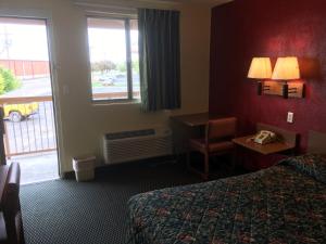 a hotel room with a bed and a desk and a window at Relax Inn West Amarillo Medical Center in Amarillo