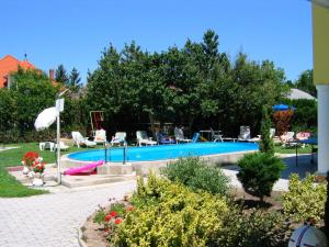 una piscina in un cortile con sedie e alberi di Barbara Wellness Pension a Keszthely