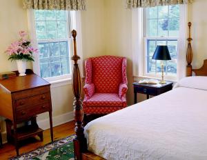 a bedroom with a bed and a chair and windows at The Griswold Inn in Essex