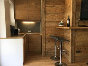 una cocina con paredes de madera y un bar con taburete. en Kitz-Studio en Kitzbühel