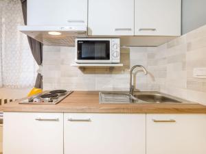 eine weiße Küche mit einer Spüle und einer Mikrowelle in der Unterkunft Navis Luxury Apartments in Vodice