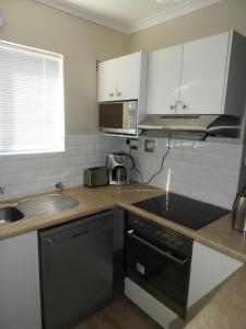 a kitchen with a sink and a stove top oven at Hermanus Beach Club 144 in Hermanus
