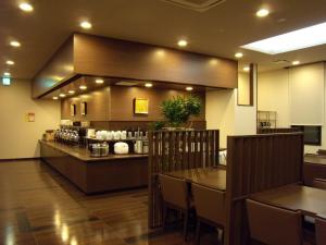 a restaurant with a counter and a table with chairs at Hotel Route-Inn Tsuruoka Ekimae in Tsuruoka
