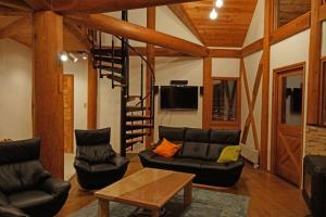 una sala de estar con muebles de cuero negro y una escalera de caracol. en Yuki-ki Lodge, en Hakuba